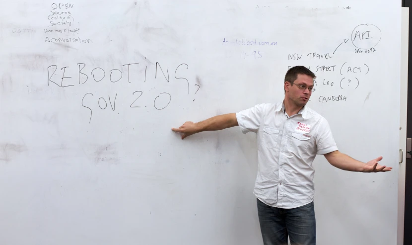 a man leaning on a white wall next to writing on it