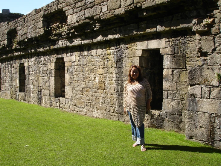 a woman posing in front of an old brick wall