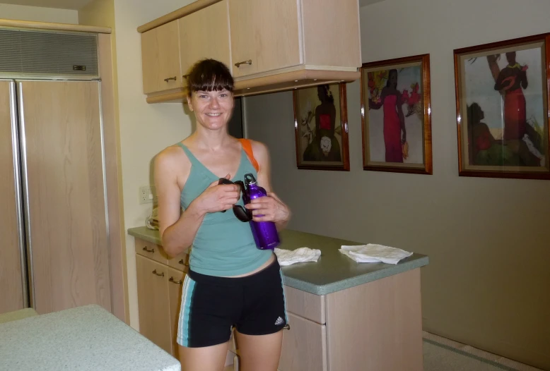 a young woman holding a purple bottle in her kitchen