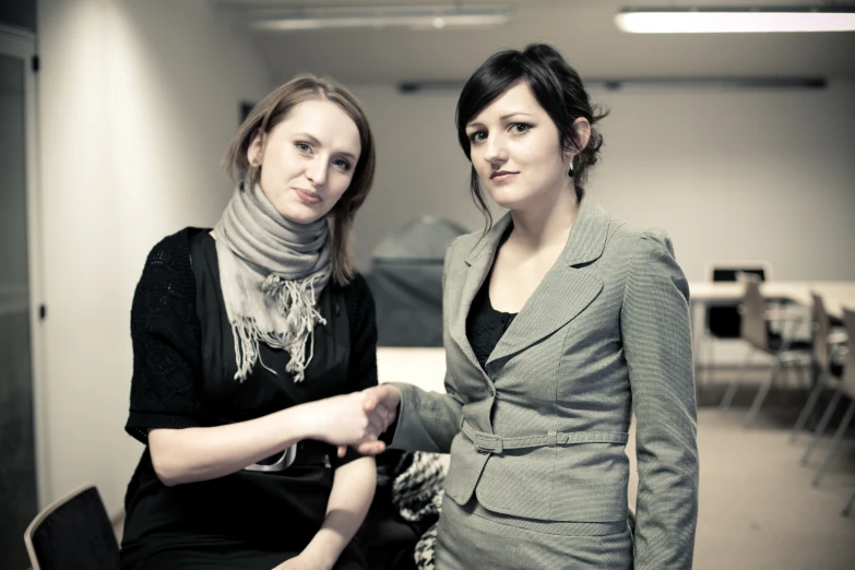 two women standing next to each other in front of a building