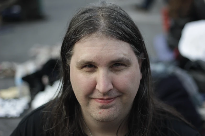 the man with long hair smiles near many bags