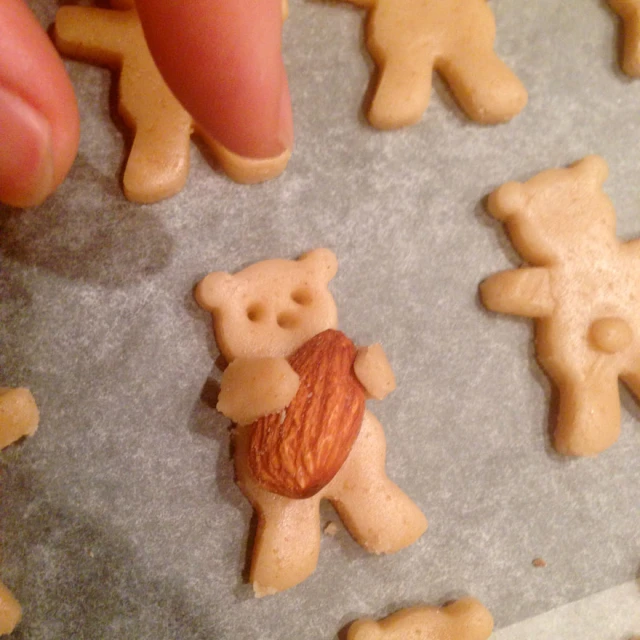 person pointing to small cookies with almonds in the shape of teddy bears