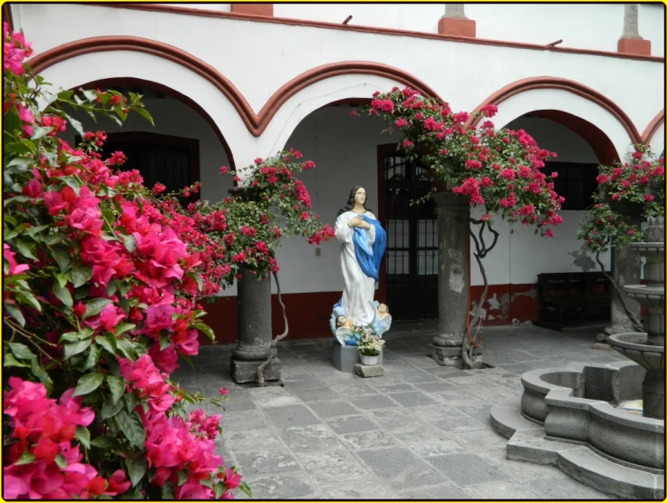 a statues in an courtyard surrounded by flowers