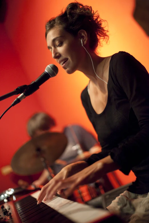 a woman with headphones sitting at a keyboard playing music