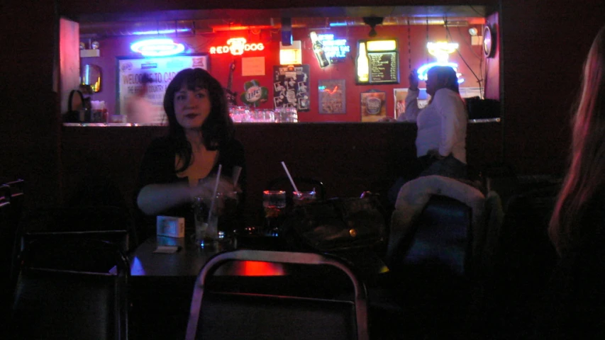 some women sitting at a bar in a dimly lit area