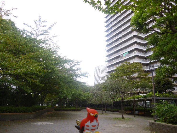 the red fire hydrant is in a park in front of tall buildings