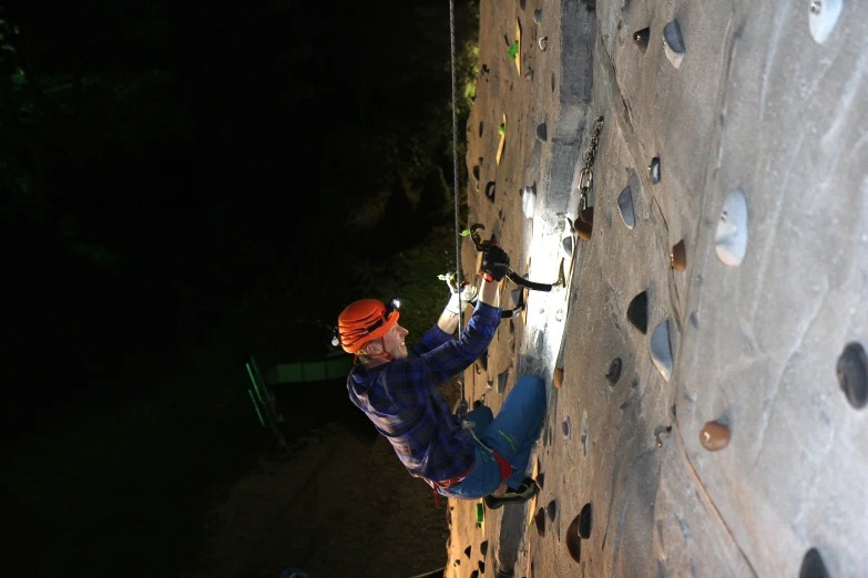 a man climbing a rock wall at night