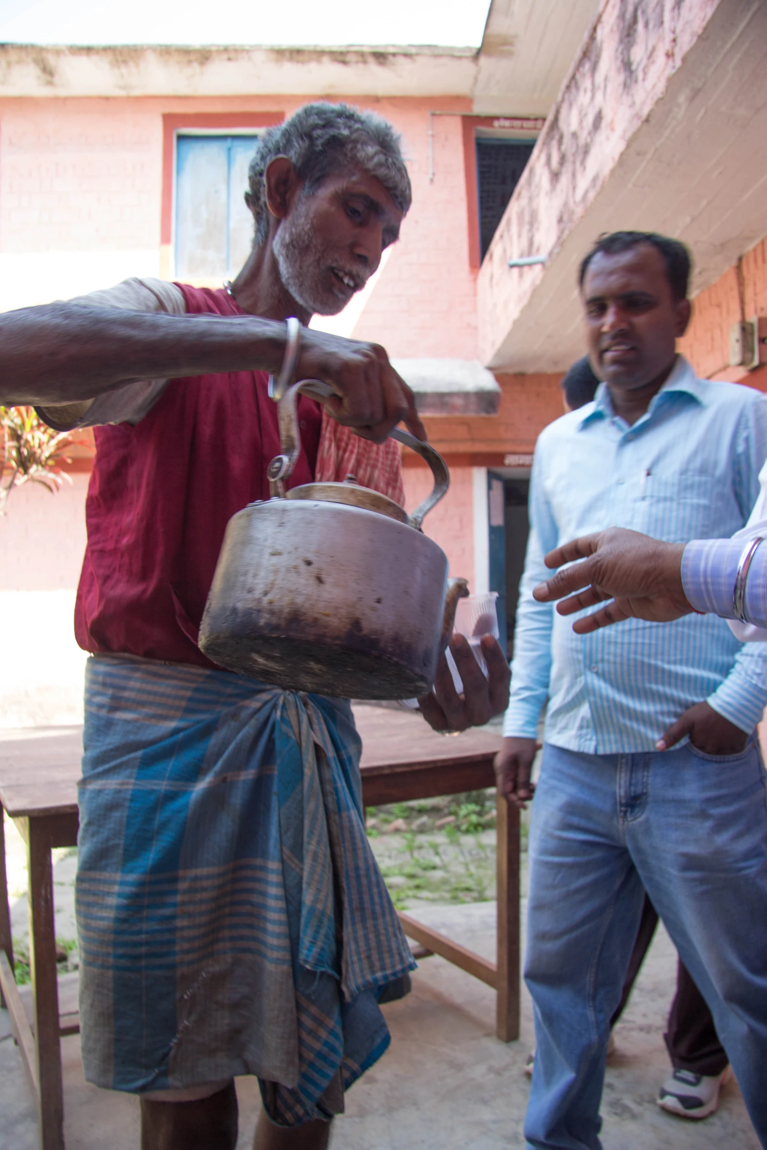 the man is stirring the liquid from the metal pot