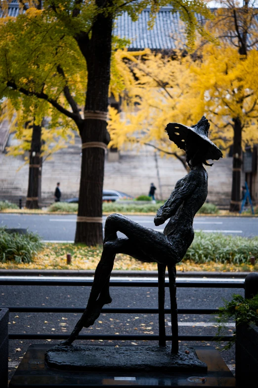 a statue of a woman sitting on top of a chair with a hat on her head