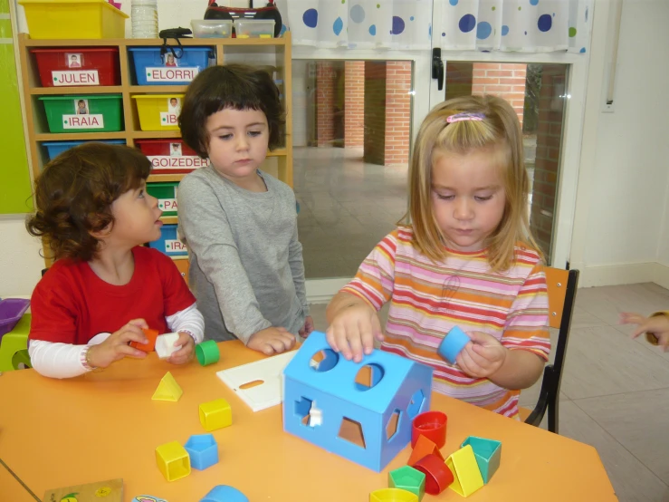 three children are sitting around a table together