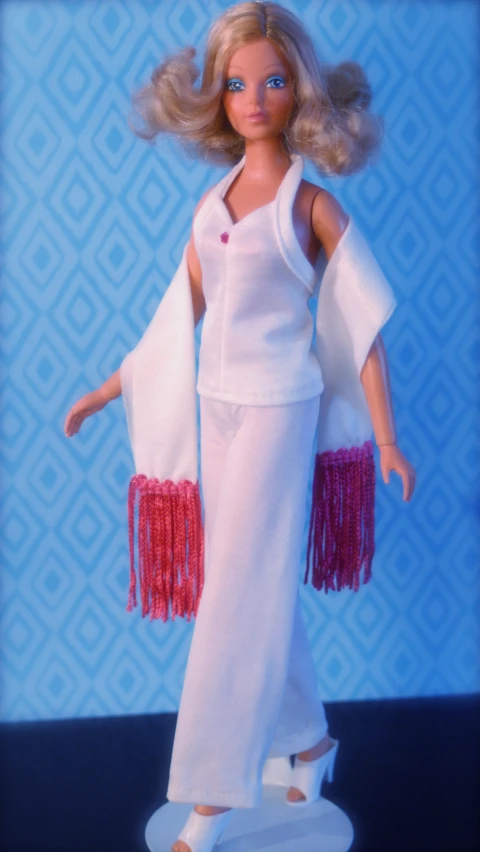 a doll is dressed in white and holding a jacket