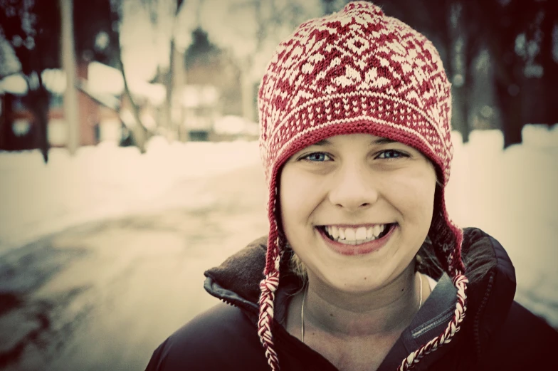 a woman in a knitted hat smiles at the camera