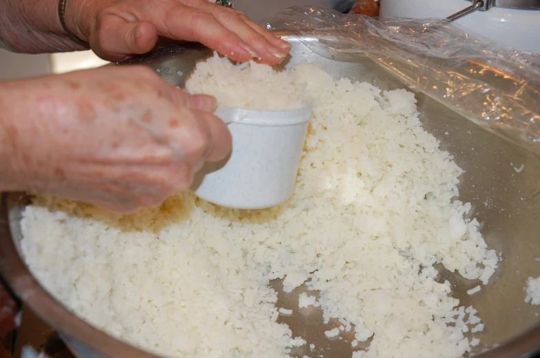 someone holding a container over some rice in a bowl