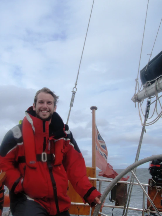 a man smiling while standing on the side of a boat