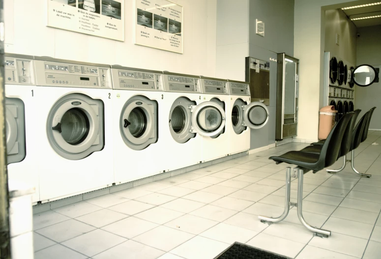 a bathroom has a row of washers and chairs