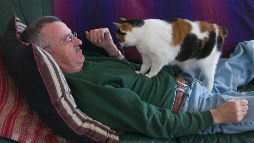 an older man sitting on a couch with his cat