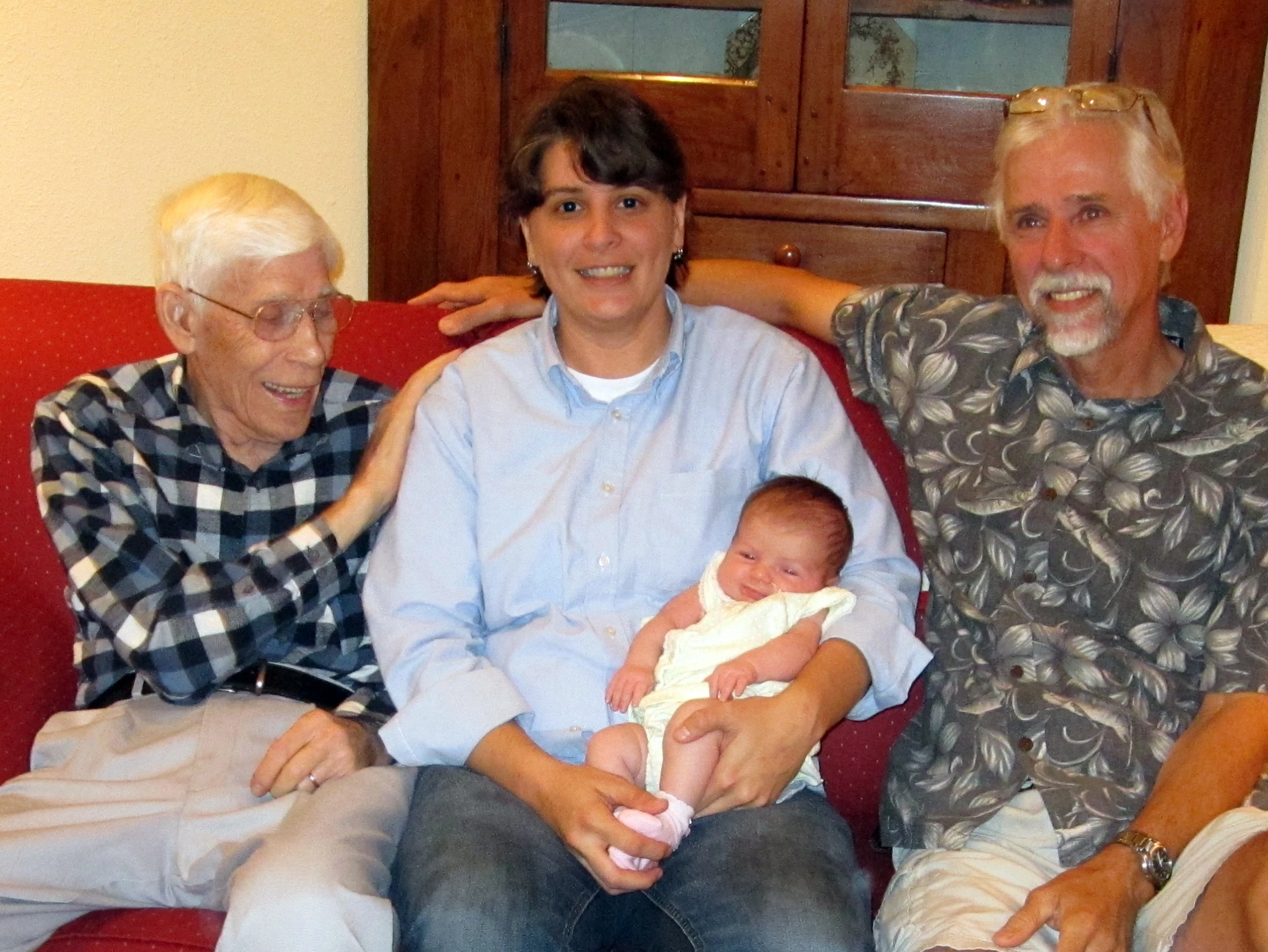 a man and a woman sitting with a baby in front of them