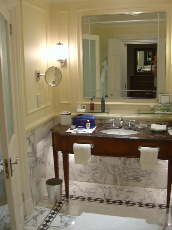 a marble bathroom with sink and large mirror