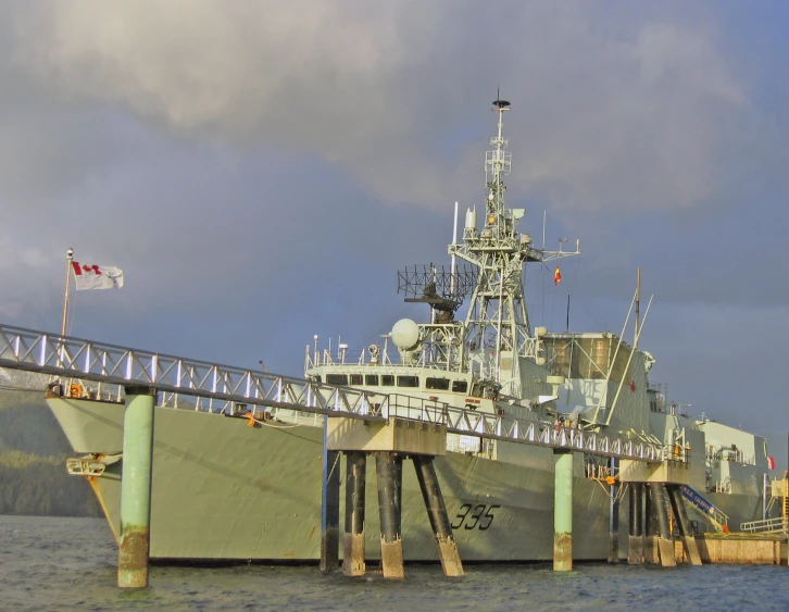 a military ship docked at the end of a pier