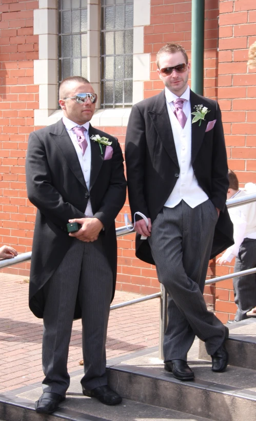 two men wearing suits and ties are standing on stairs