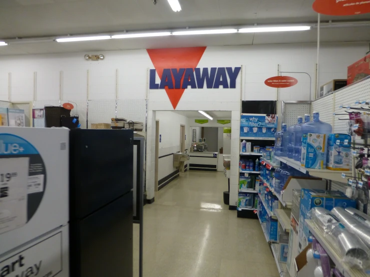 an empty store with boxes of water on the floor and a lavatory sign on the wall