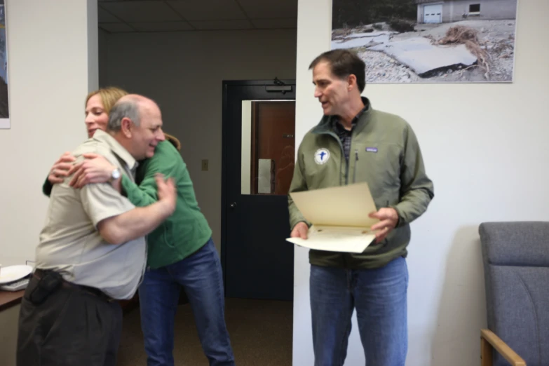 two people hugging and smiling in an office setting