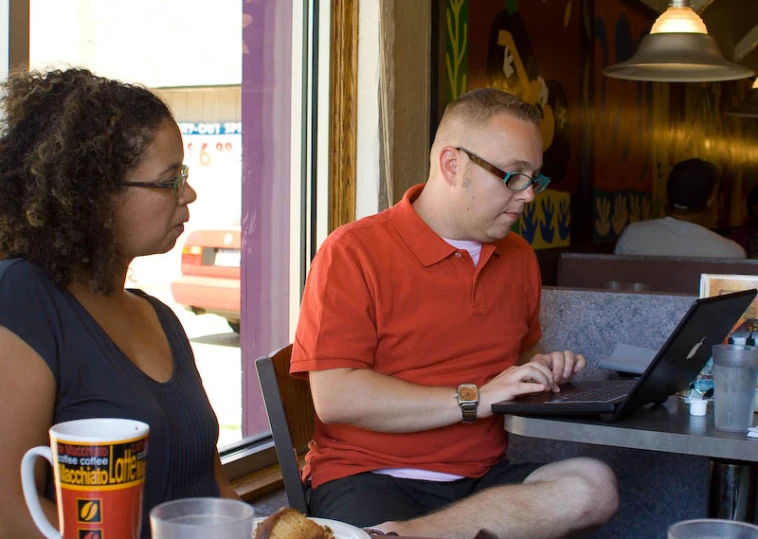 two people sitting at a table using laptop computers