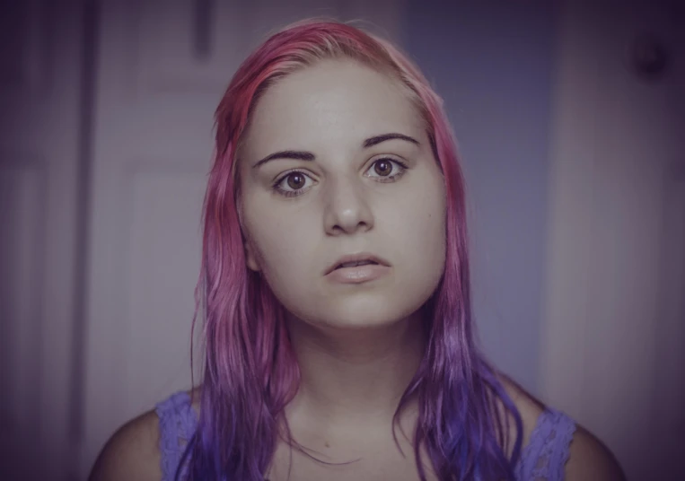 a woman with pink hair and blue dress looking at soing