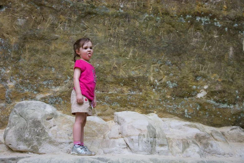 little girl looking over her shoulder on rocks