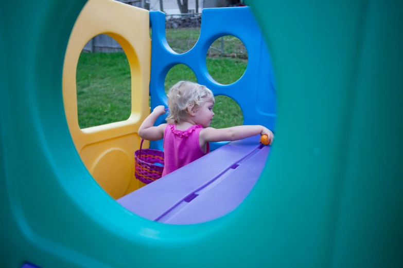 a girl is playing in a small colorful playground