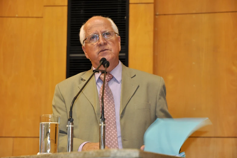 an older man with glasses speaking into microphone