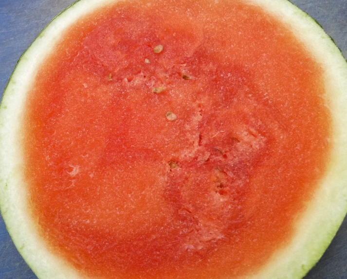 a red melon is cut in half on a blue tablecloth