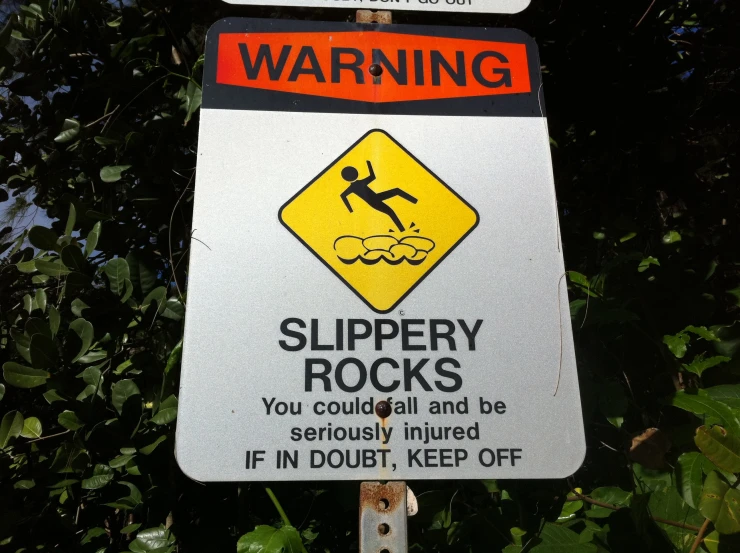 a warning sign stating slippery rocks and how to be outrund