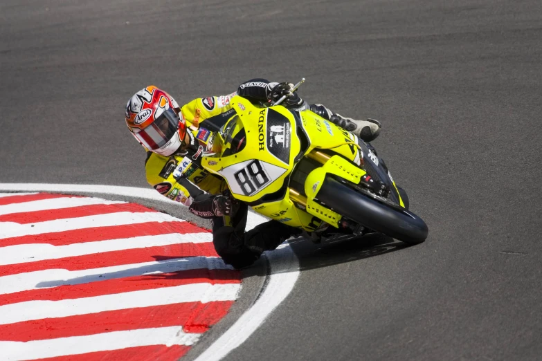 a man wearing yellow racing gear leans to adjust his helmet