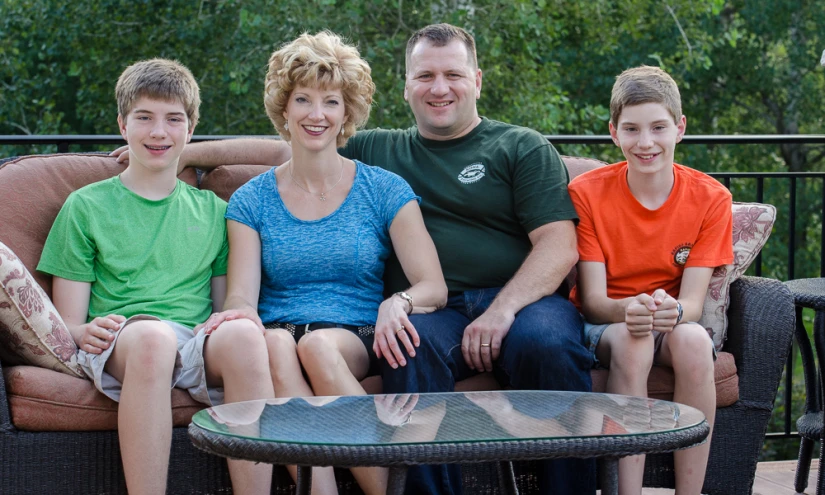 three people sit on a couch with an infant