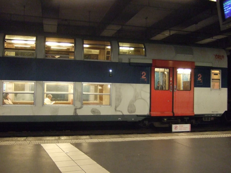 train stopped at a subway station, with passengers waiting for their train to come