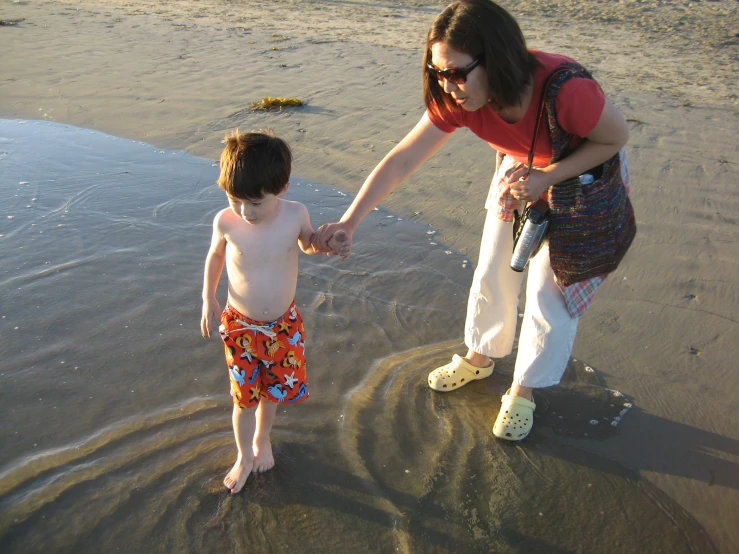 a child standing next to an adult holding their hand