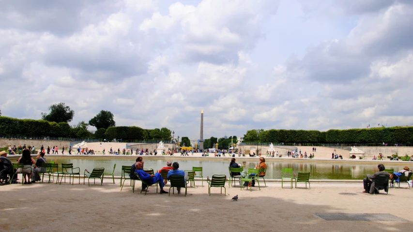 people sitting on chairs on a walkway by a water feature