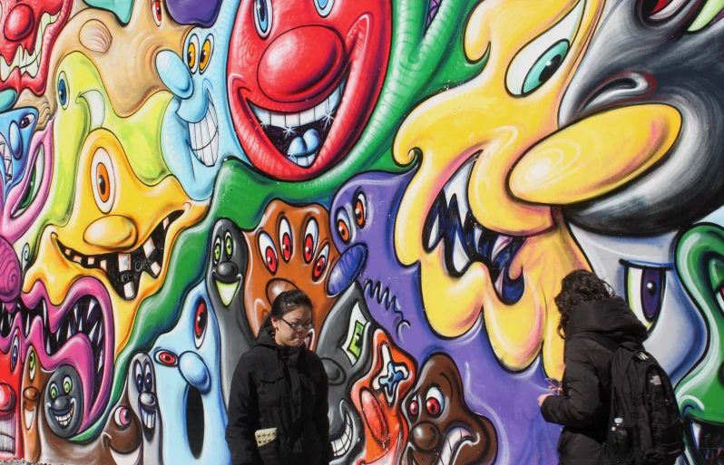 the men are standing against the graffiti on the wall