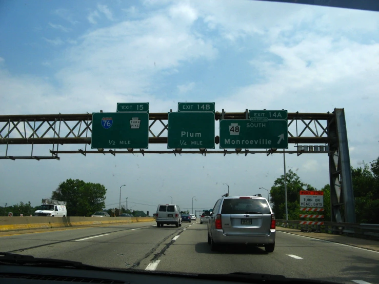 some green signs are above the road on a freeway