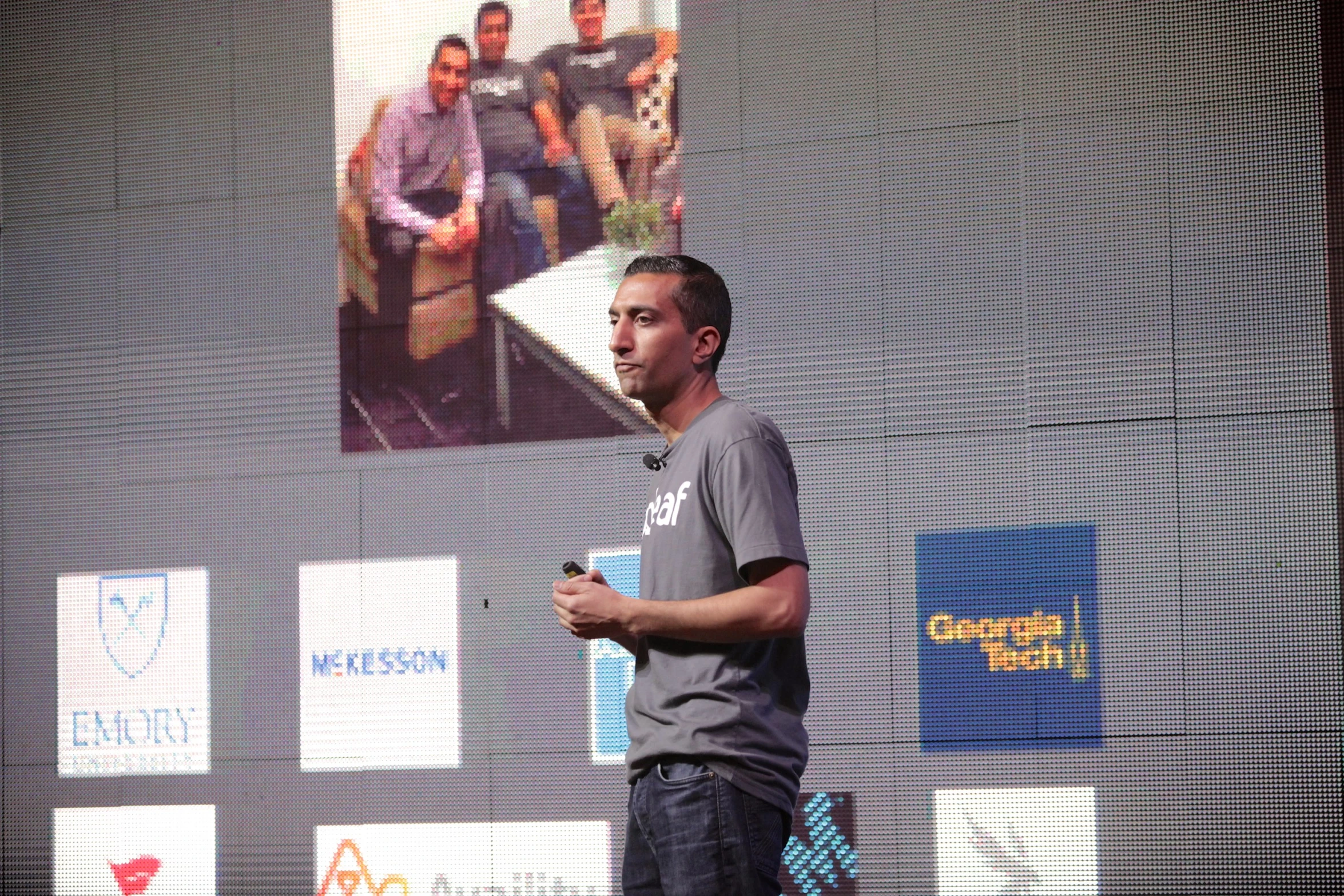 man on cell phone standing in front of screen holding microphone