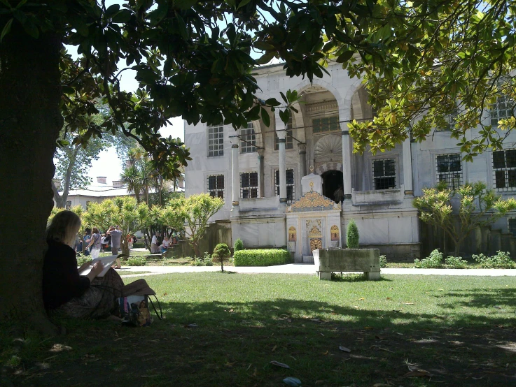 a man sitting on a bench in front of a very large house