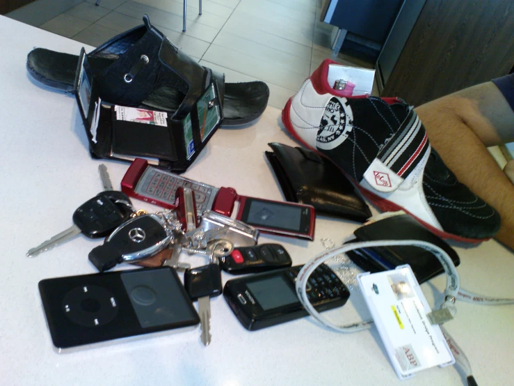 a table filled with keys, cell phones and shoes