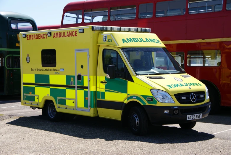 an ambulance car is parked near some double decker buses