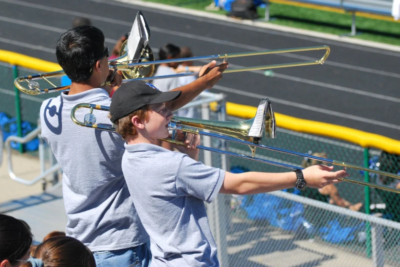 two boys playing musical instruments on a baseball field