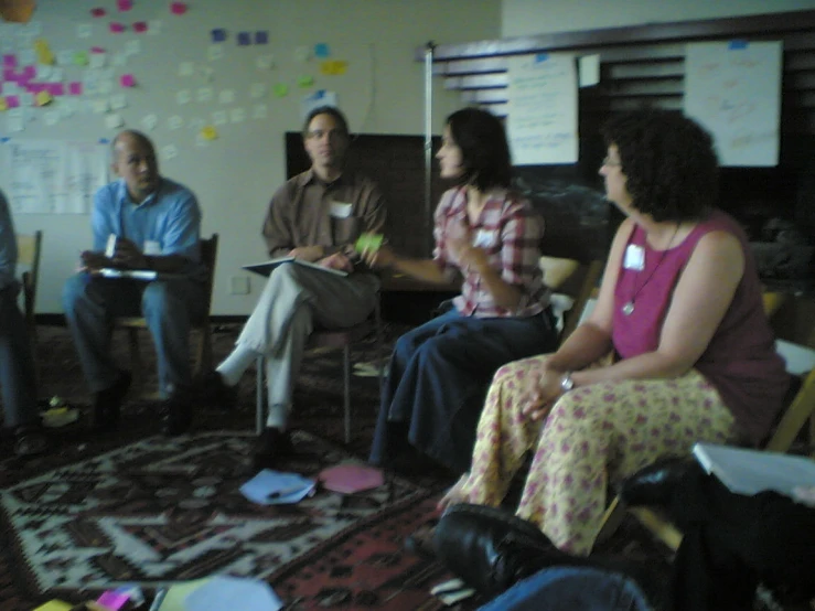 several people sitting on chairs talking and having discussion