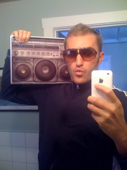 a man holding up a boom box while looking at his cell phone