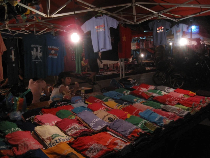 men shop for t - shirts at an outdoor street market