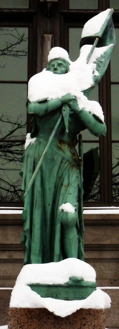 a statue with snow all over it standing in front of a building