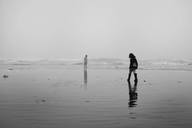 two people are standing on the beach looking at the ocean